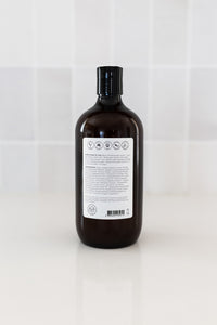 Bottle of dog shampoo with natural ingredients, sulphate and paraben free with spiced cucumber, lavender and tea-tree scent in a bathroom. Back label view.